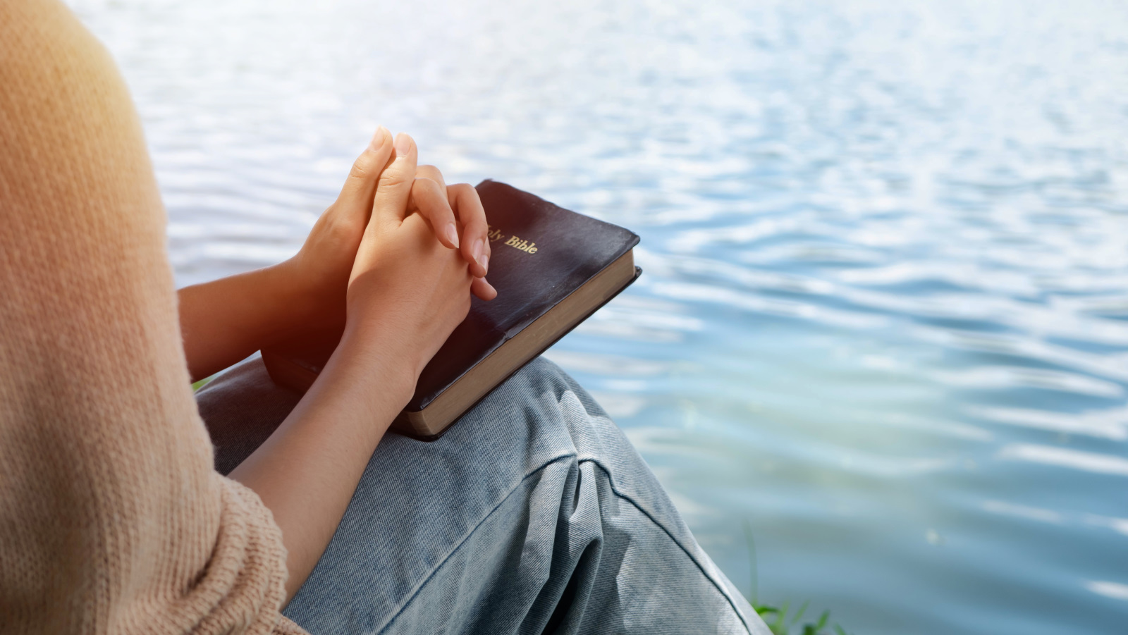 Woman hands holding bible and praying at river in the morning Brigade